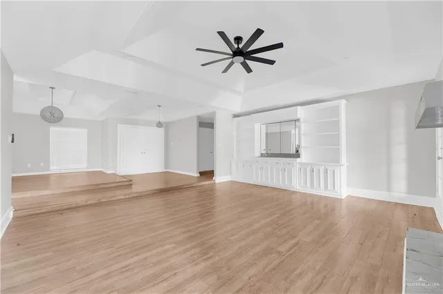 a view of empty room with wooden floor and ceiling fan