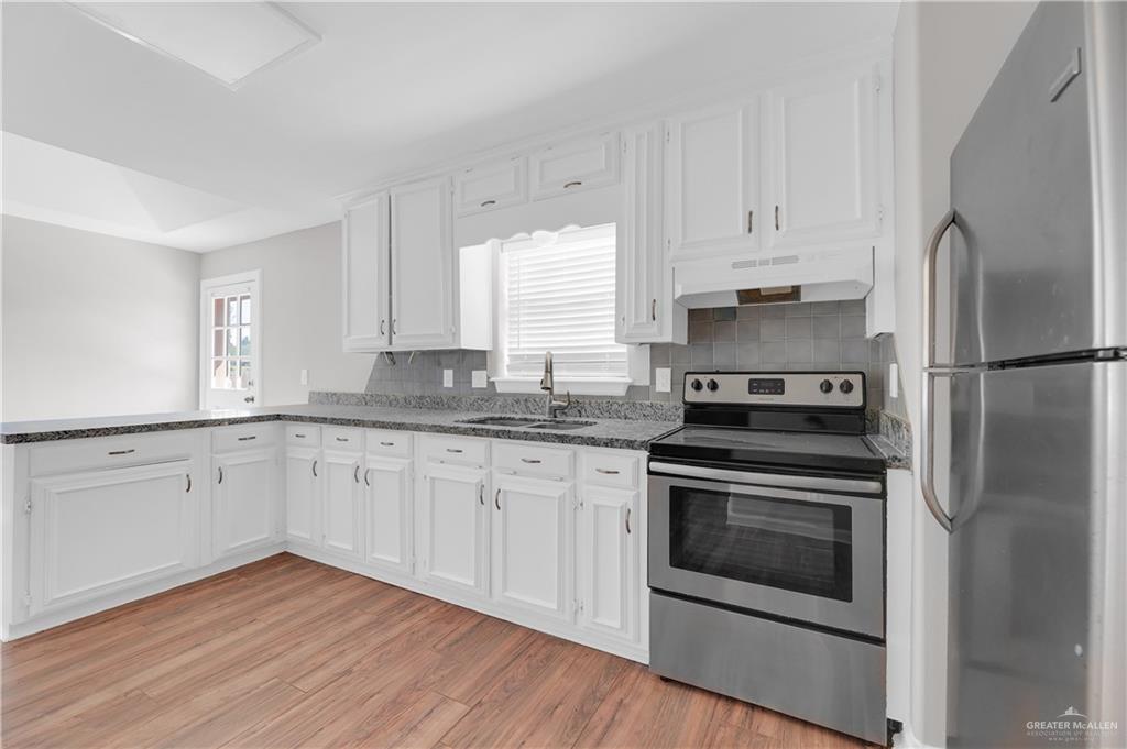 7008 North 30th Street McAllen, TX 78504 - Photo 8 of 18 a kitchen with granite countertop white cabinets stainless steel appliances and sink
