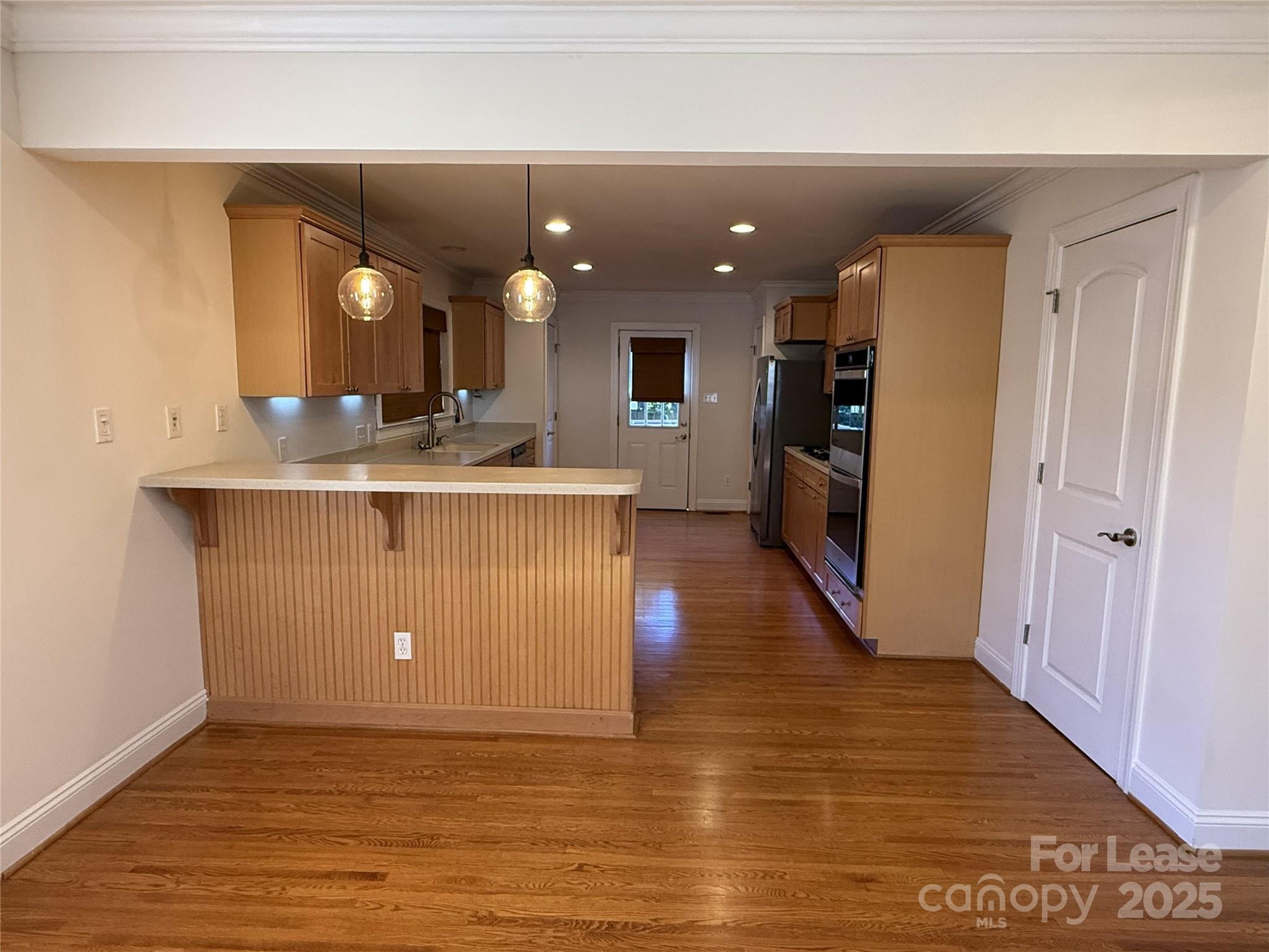 350 Melbourne Court Charlotte, NC 28209 - Photo 5 of 22 a view of a kitchen with kitchen island a sink wooden floor and a refrigerator