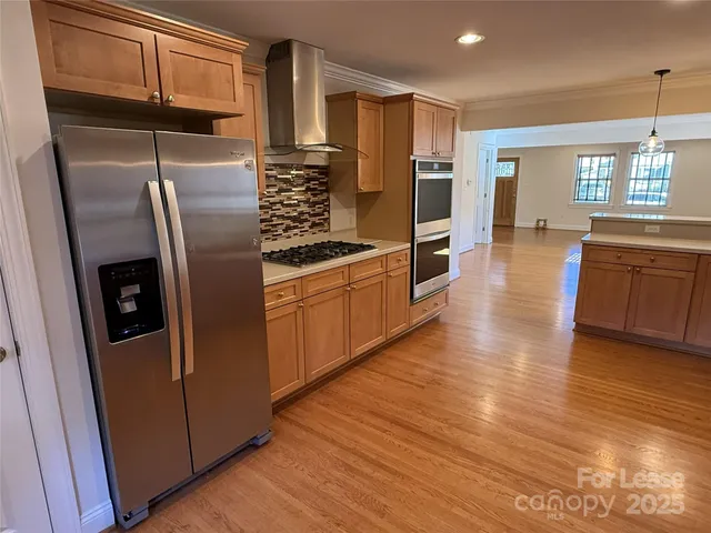a kitchen with stainless steel appliances granite countertop a refrigerator a stove and a wooden floors