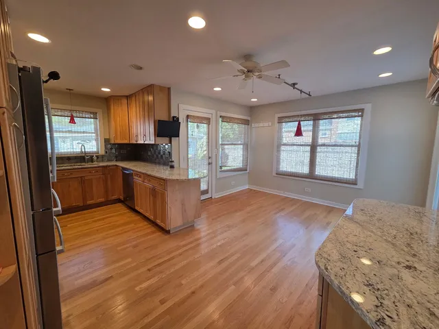 a kitchen with stainless steel appliances granite countertop a refrigerator a sink dishwasher a stove and a microwave oven on the wooden floor