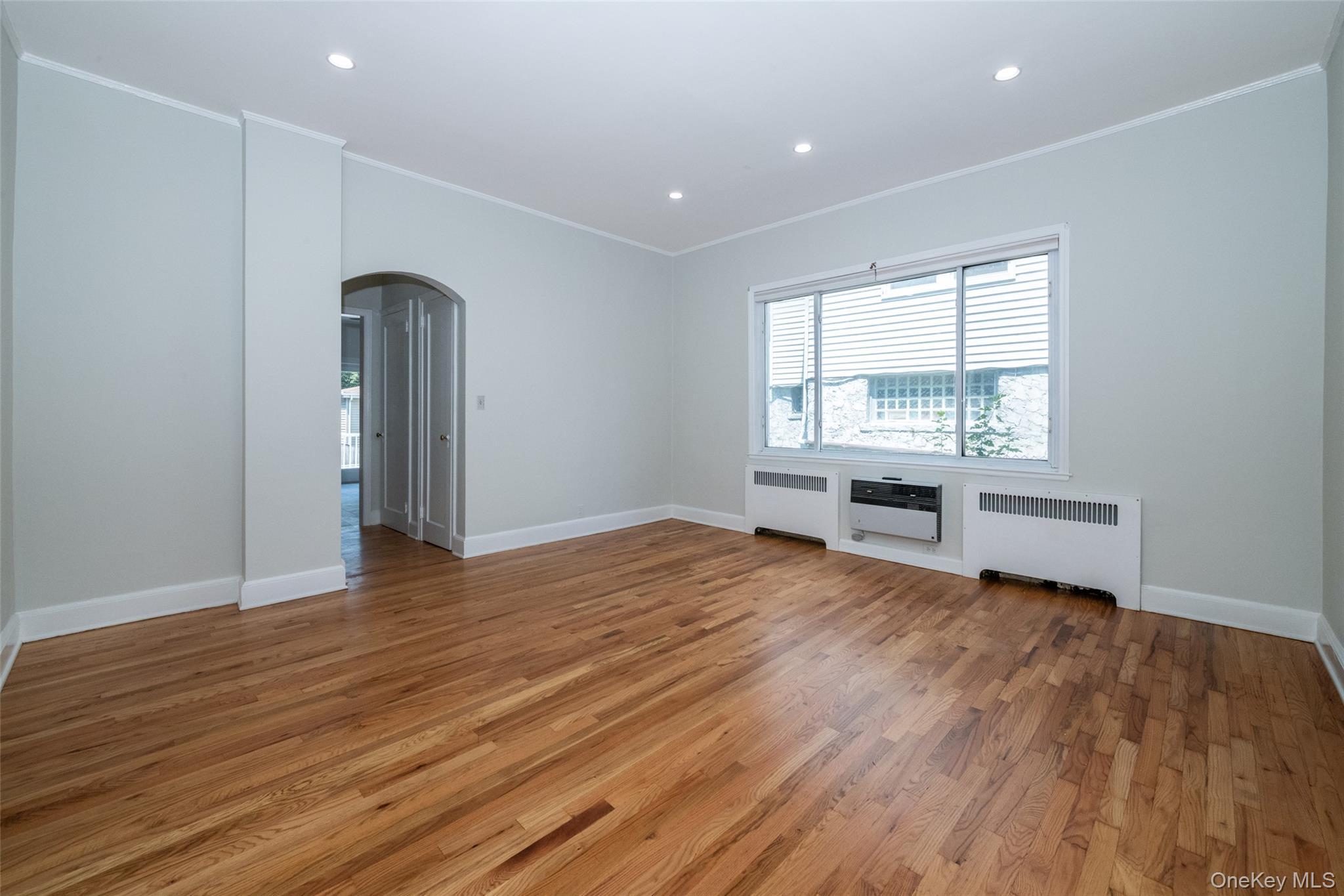 7 Alpha Place, Unit FIRST New Rochelle, NY 10805 - Photo 14 of 25 Spare room featuring radiator heating unit, arched walkways, ornamental molding, light wood-type flooring, and recessed lighting