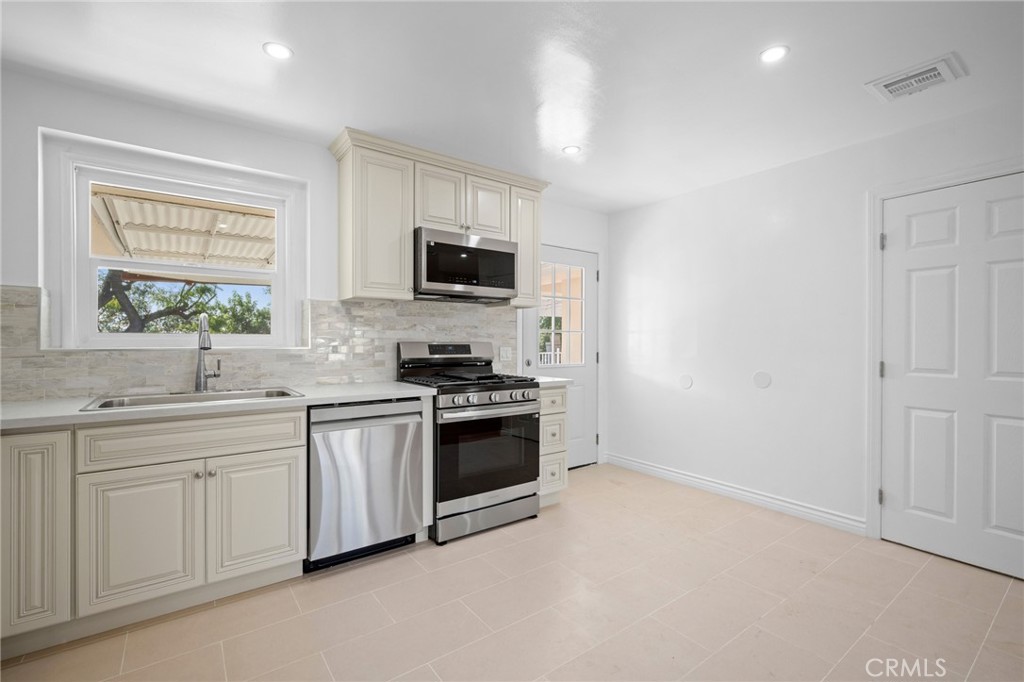 685 Rim Road Pasadena, CA 91107 - Photo 11 of 27 a kitchen with stainless steel appliances a sink a stove a microwave a refrigerator a window and cabinets