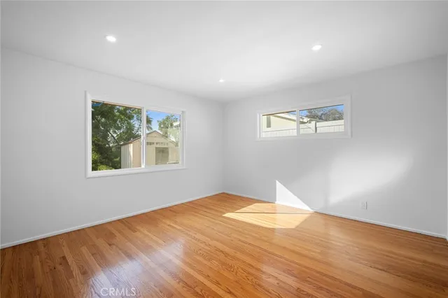 a view of empty room with wooden floor and fan