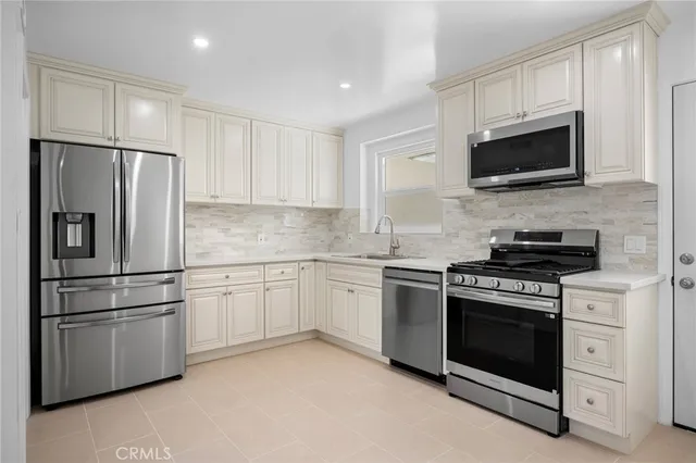 a kitchen with stainless steel appliances white cabinets white stove a microwave and a refrigerator