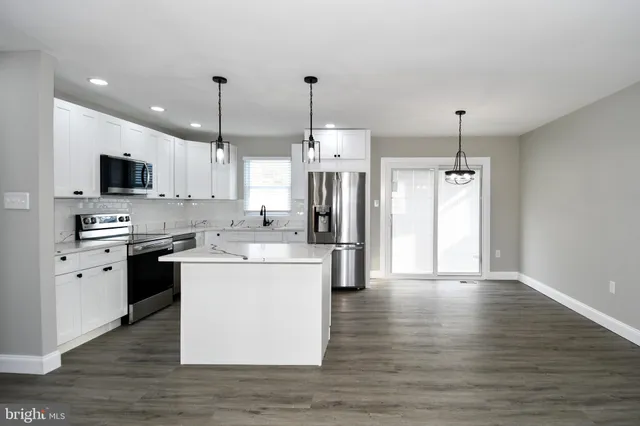 a kitchen with kitchen island white cabinets stainless steel appliances and wooden floor