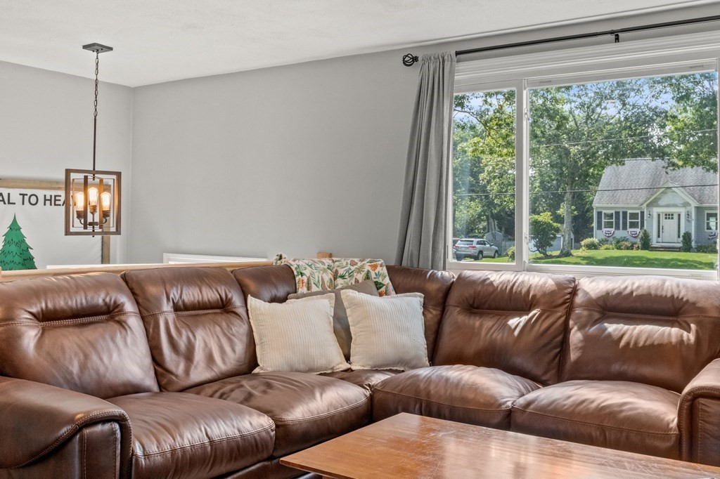 61 Thom Avenue Bourne, MA 02532 - Photo 8 of 32 a blue couch sitting in a living room next to a window