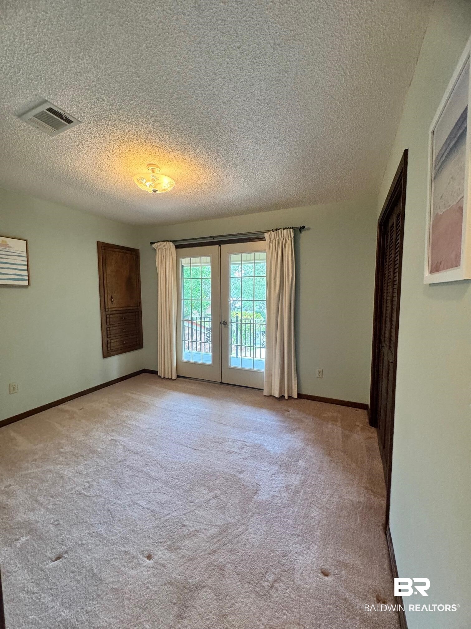 2240 Perdido Circle Lillian, AL 36549 - Photo 18 of 42 Spare room featuring a textured ceiling, light colored carpet, and french doors