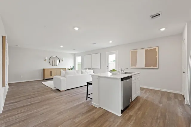 a living room with stainless steel appliances granite countertop furniture wooden floor and a window