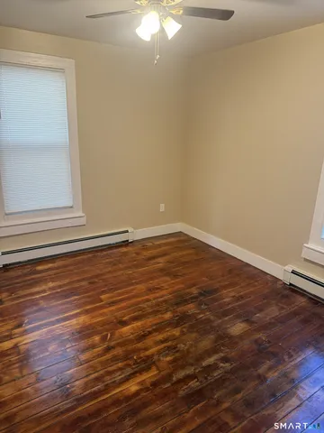 a view of an empty room with wooden floor and a window