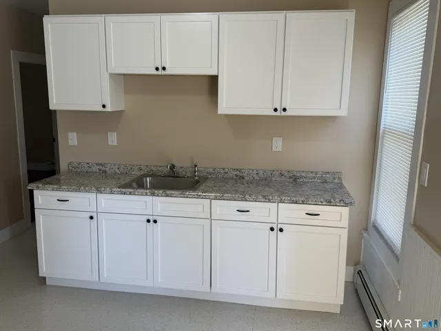 a kitchen with granite countertop white cabinets and a stove