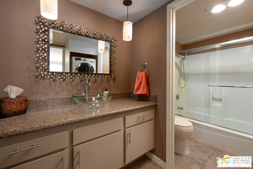 325 East Via Escuela, Unit 324 Palm Springs, CA 92262 - Photo 19 of 29 a bathroom with a granite countertop sink a toilet a mirror and shower