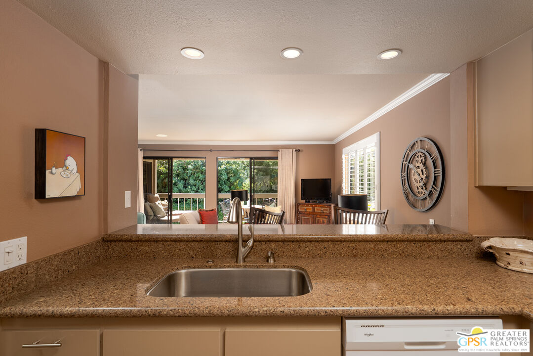 325 East Via Escuela, Unit 324 Palm Springs, CA 92262 - Photo 7 of 29 a kitchen with granite countertop a sink and a stove with wooden floor