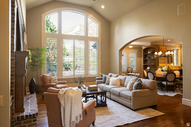 875 South 1250th Street East Mapleton, UT 84664 - Photo 19 of 54 Vaulted ceiling great room featuring a tall arched window with plantation shutters, a brick fireplace with a wood mantel, and wood-finish flooring