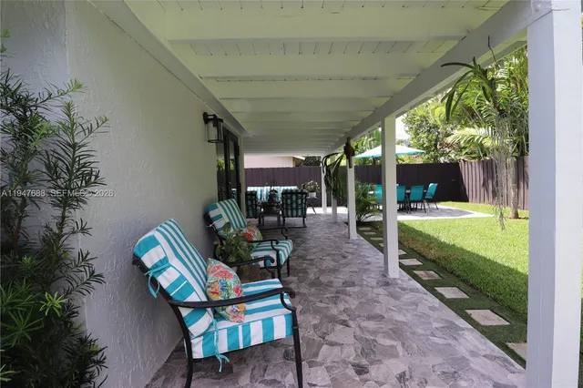 a view of a patio with table and chairs potted plants with floor to ceiling window