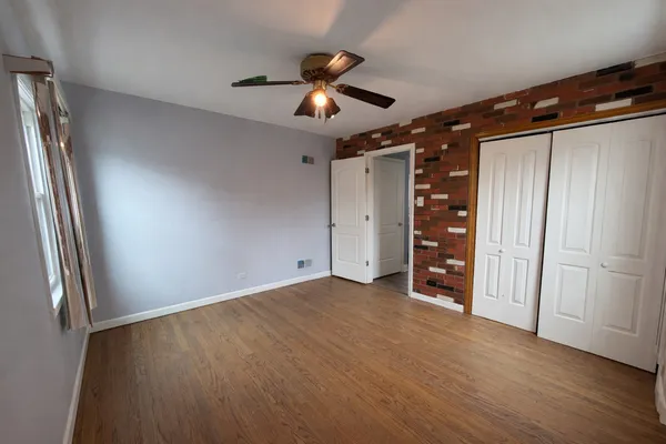 an empty room with wooden floor closet and windows