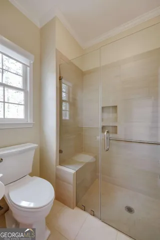a view of a hallway with wooden floor and a bathroom