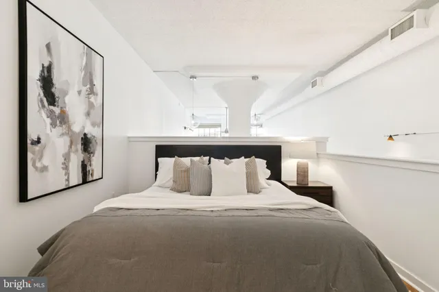 a bedroom with a large bed and a lamp on the dresser