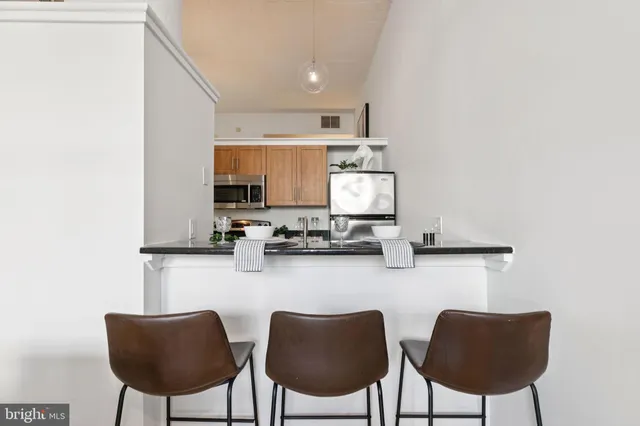 a kitchen with stainless steel appliances a dining table chairs and a refrigerator