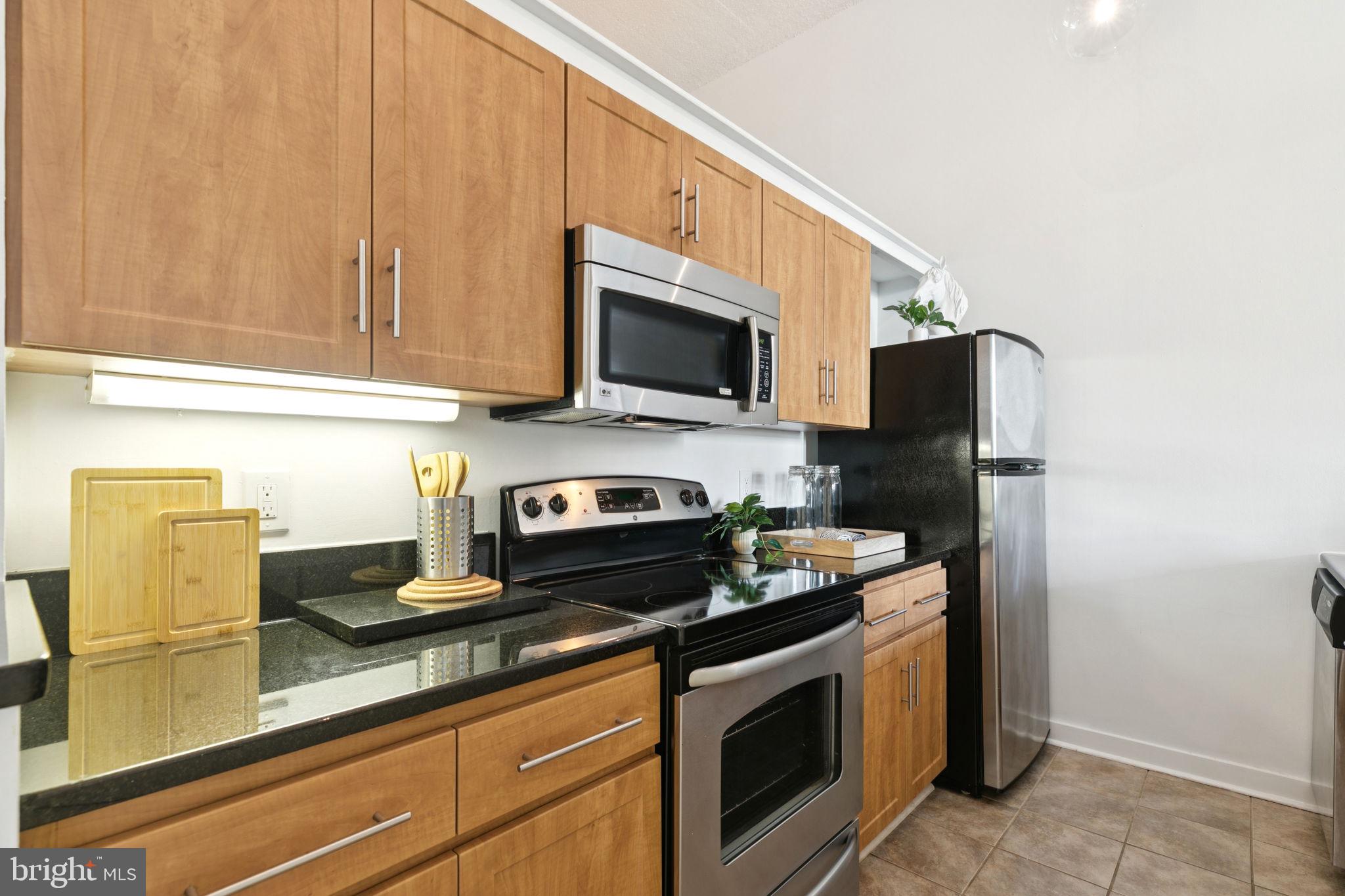 2429 Locust Street, Unit 318 Philadelphia, PA 19103 - Photo 9 of 35 a kitchen with stainless steel appliances granite countertop a stove a microwave and a refrigerator