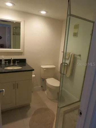 a bathroom with a granite countertop sink toilet and mirror