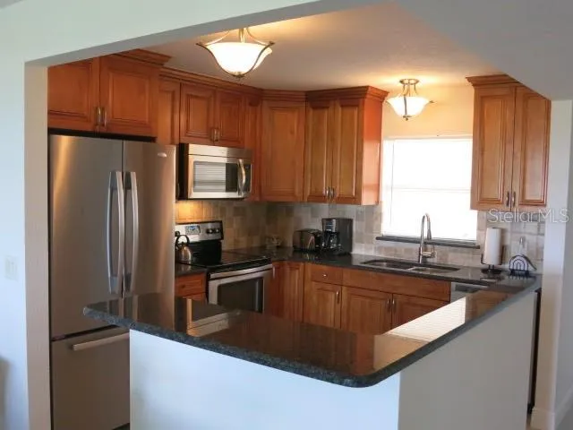a kitchen with granite countertop a refrigerator stove and sink