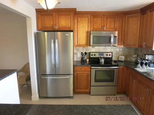 a kitchen with granite countertop a refrigerator stove and microwave