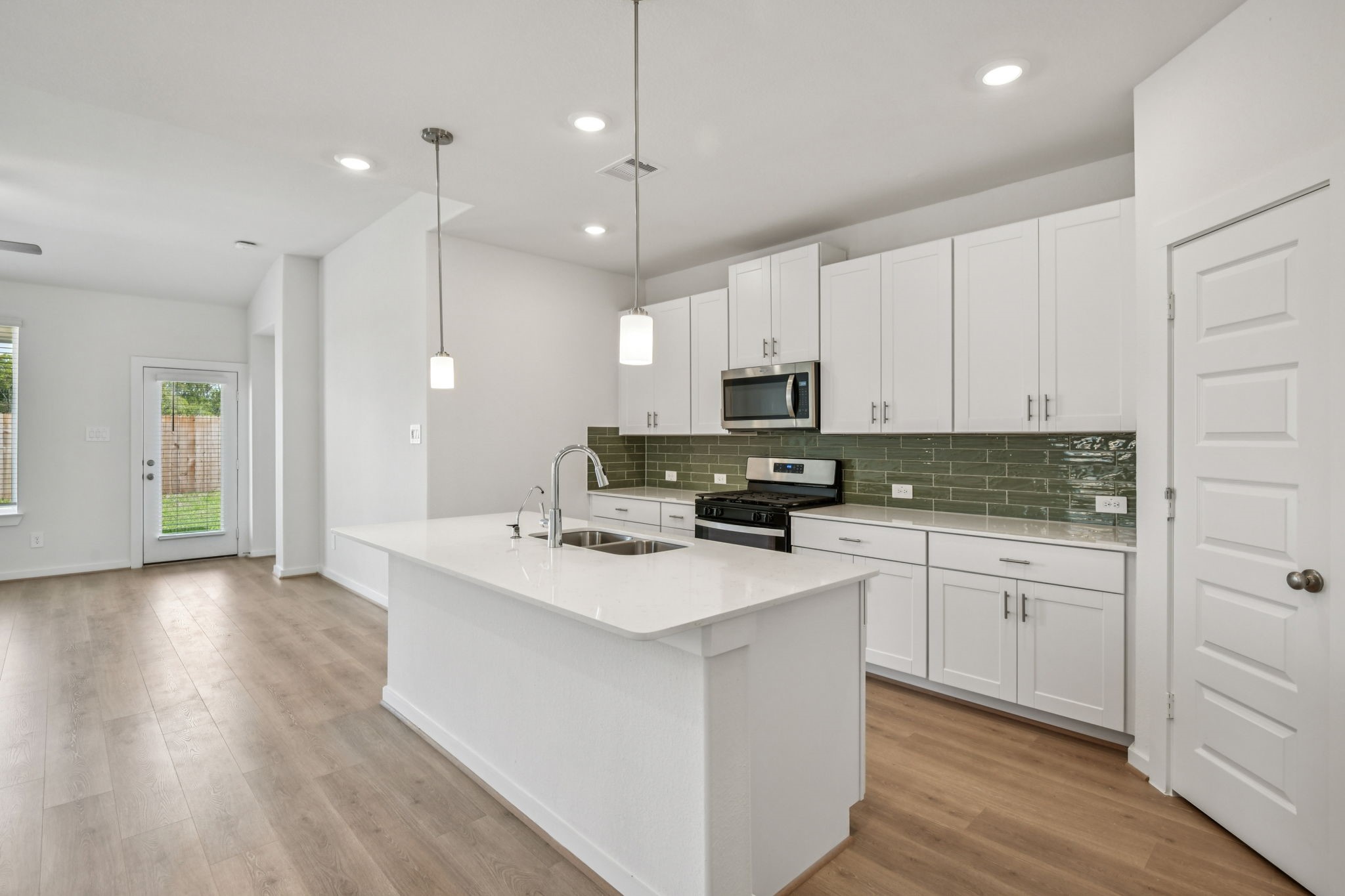 a kitchen with stainless steel appliances kitchen island granite countertop a stove a sink and white cabinets with wooden floor