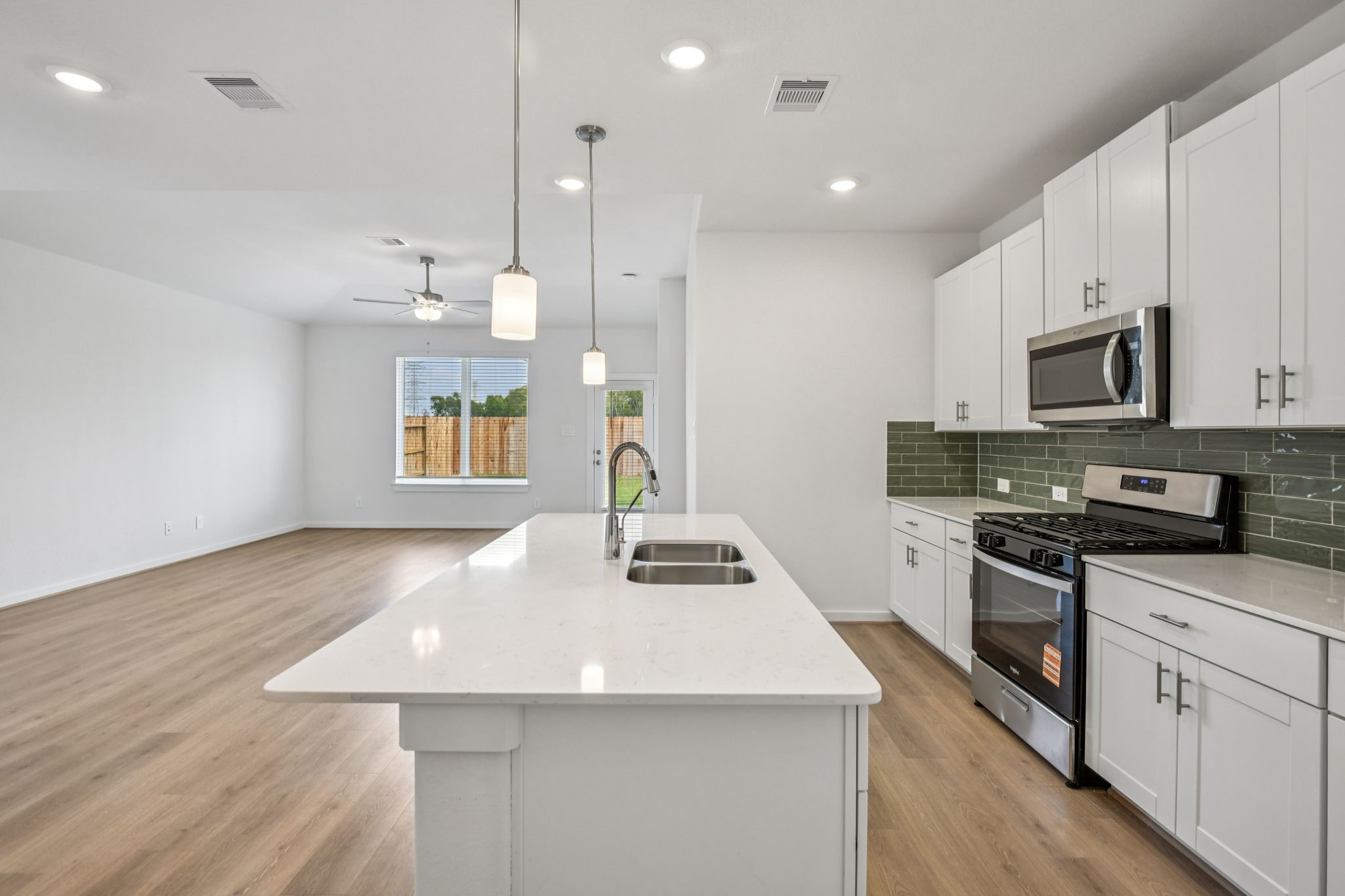 6631 Castella Drive Rosharon, TX 77583 - Photo 17 of 47 a kitchen with kitchen island a stove a sink a oven and a dining table with wooden floor