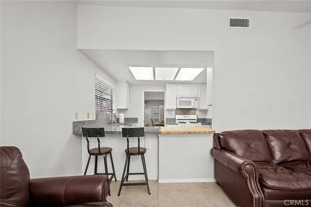 a view of kitchen with stainless steel appliances granite countertop and chairs