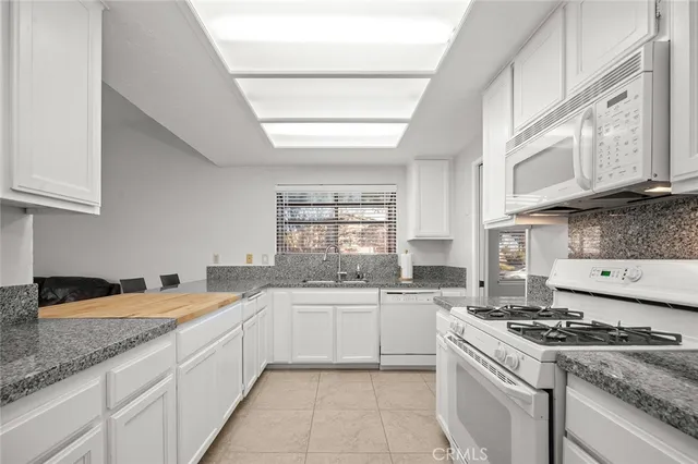 a kitchen with stainless steel appliances granite countertop a sink stove oven and white cabinets