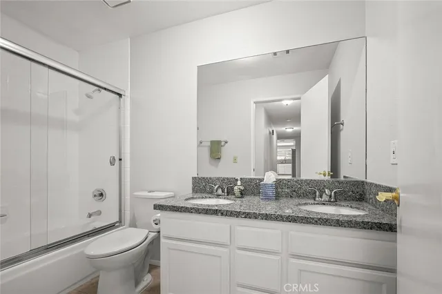 a bathroom with a granite countertop sink a toilet and a large mirror