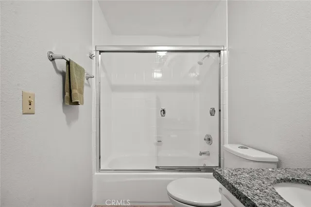 a bathroom with a granite countertop toilet a sink and shower
