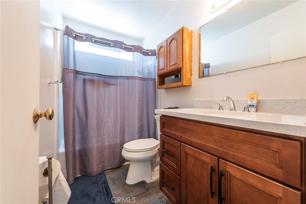 6732 San Joaquin Way Riverside, CA 92503 - Photo 6 of 25 a bathroom with a sink a toilet a mirror and shower curtain