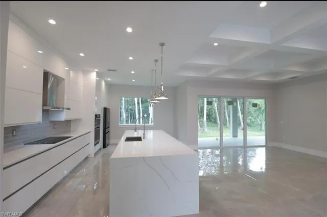 a large white kitchen with large windows and refrigerator