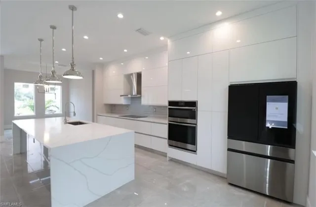 a kitchen with stainless steel appliances kitchen island granite countertop a refrigerator and a sink