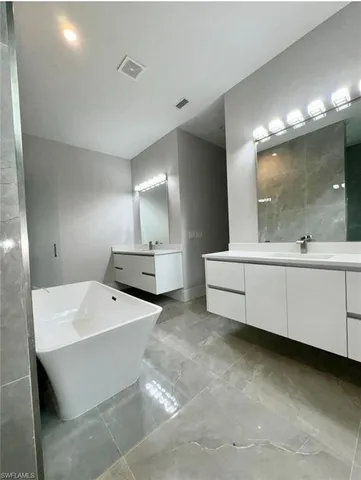a bathroom with a double vanity sink mirror and bathtub