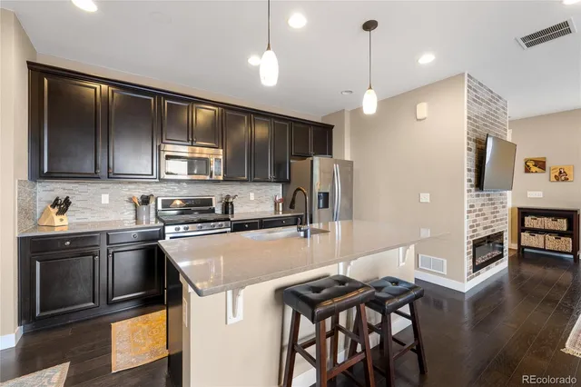 a kitchen with stainless steel appliances granite countertop a stove top oven a sink dishwasher a dining table and chairs with wooden floor