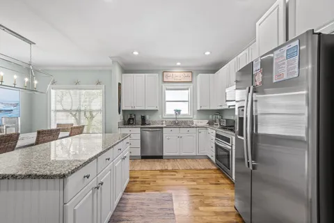 a large kitchen with granite countertop a large counter top appliances and cabinets
