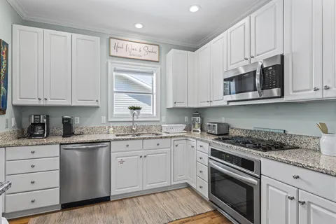 a kitchen with stainless steel appliances granite countertop white cabinets granite counter tops and a wooden floors