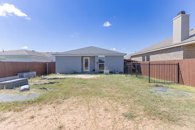 a view of a house with a yard and wooden fence
