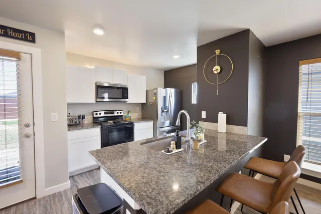 a kitchen with kitchen island granite countertop a sink dining table and chairs