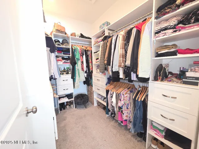a view of walk in closet with clothes and shoes