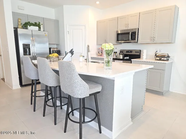 a kitchen with stainless steel appliances granite countertop a sink a stove a microwave a refrigerator and cabinets