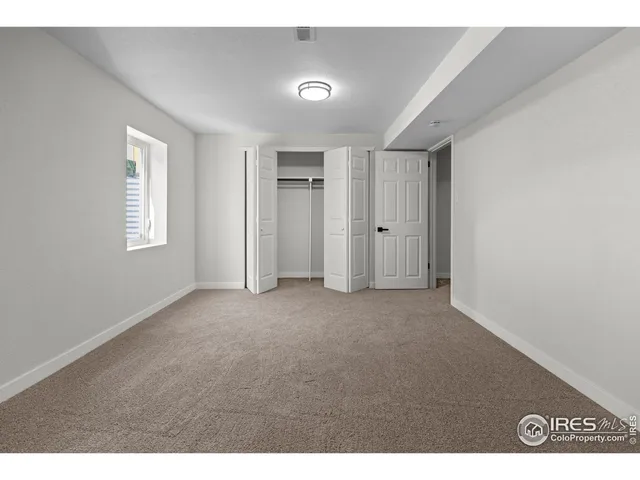 a view of an empty room with window and closet area