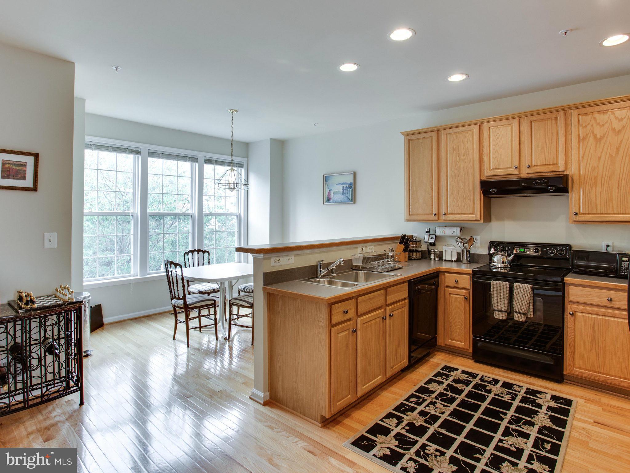 9823 Darcy Forest Drive Silver Spring, MD 20910 - Photo 17 of 30 a kitchen with a stove a sink a dining table and chairs