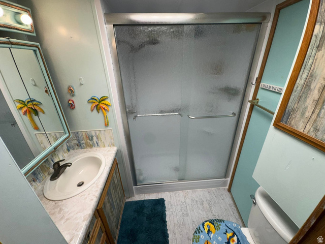1225 North Dixie Downs Road, Unit 100 St. George, UT 84770 - Photo 15 of 22 Shower with frosted glass enclosure, single vanity with integrated sink, and wood-finish cabinetry