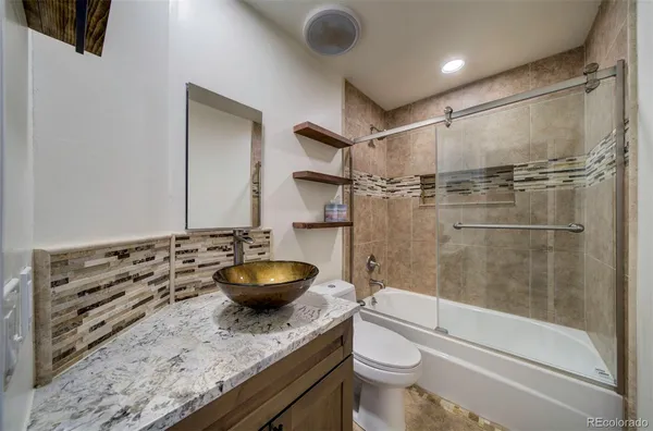 a bathroom with a granite countertop sink toilet and shower