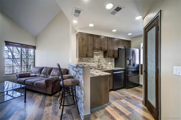 a living room with stainless steel appliances kitchen island granite countertop furniture and wooden floor