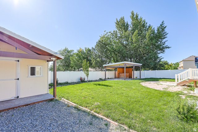 5525 Hampton Way Stansbury Park, UT 84074 - Photo 32 of 35 Expansive backyard featuring a lush lawn, gravel path, a covered patio structure, and a dedicated sand area
